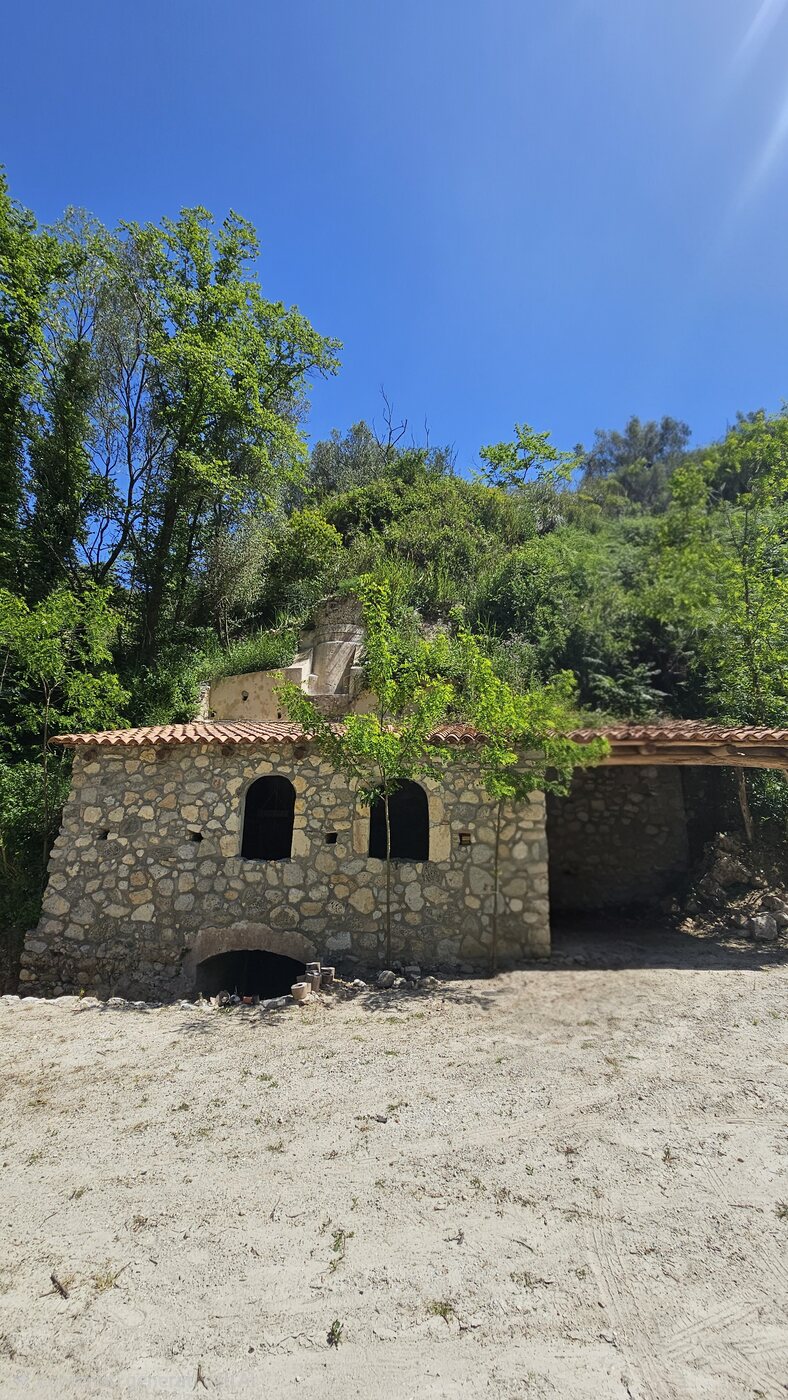 Il mulino antico restaurato in pietra immerso nel verde della valle — The restored stone watermill surrounded by the green valley